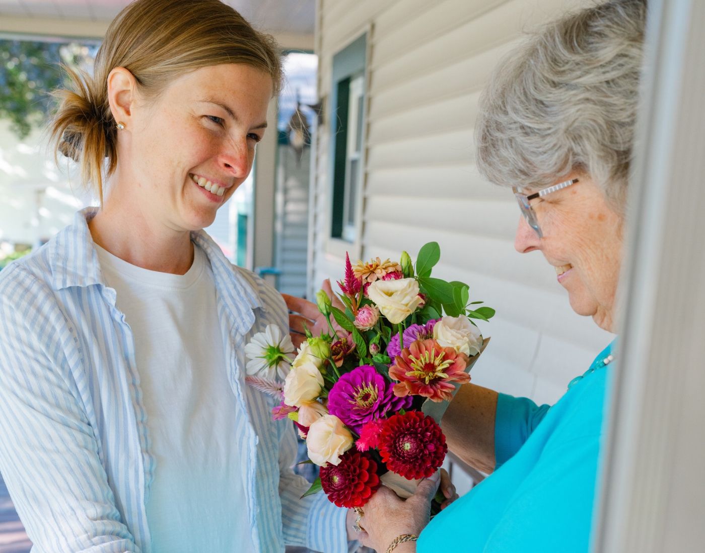 A vased flower delivery being handed to a smiling mother at her door